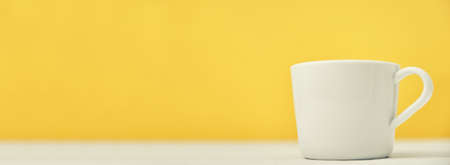 White cup on yellow background with copy space, long bannerの写真素材