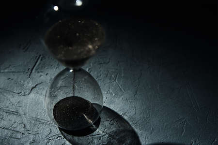 Hourglass on dark background, close up. Urgency and running out of time conceptの写真素材