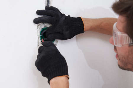 Electrician man instalation socket for wiring in concrete wall. Renovation conceptの写真素材