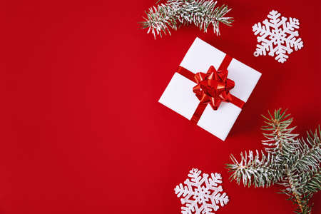 Christmas composition. Gift box with festive ribbon and christmas decorations on red background with a copy space, top viewの写真素材