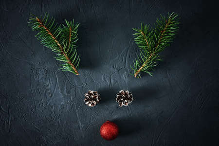 Christmas deer made of fir tree branches, pine cones and festive bauble on a dark background....