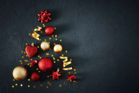 Christmas tree made of red and golden baubles and festive ribbons on a dark background with copy...