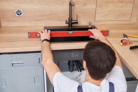 Male plumber installs a sink in the kitchen