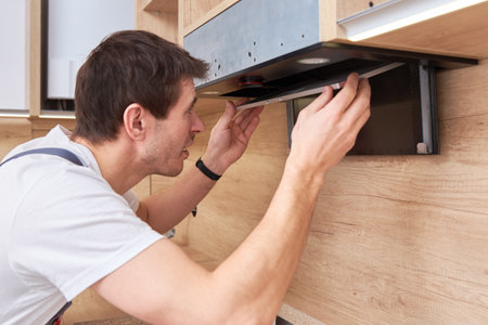 Man repairs hood in the kitchen. Replacement filter in cooker hoodの写真素材