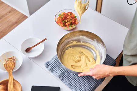 Woman in the kitchen cooking a cake. Hands beat the dough with mixer