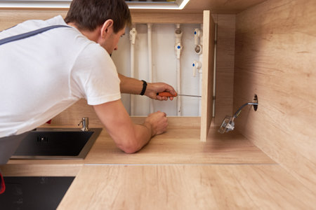 Man opens an assembly hatch and checks the water pipesの写真素材