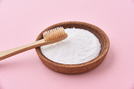 Bamboo toothbrush and baking soda on a pink background. Zero waste conceptの写真素材