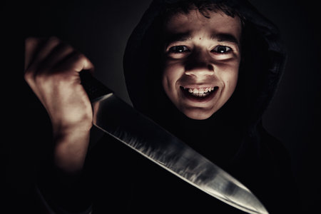 Boy in a hoodie with knife in hand. Violent boy. Juvenile delinquent concept
