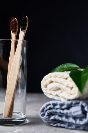 Bamboo toothbrushes in glass and bathroom towels on a dark backgroundの写真素材