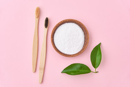 Two wooden bamboo toothbrushes and baking soda on a pink background. Eco friendly toothbrushes, zero waste conceptの写真素材