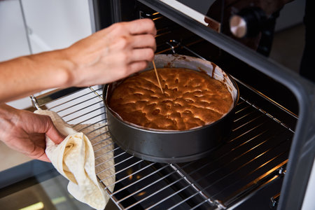 Housewife prepares cake in kitchen. Homemade cake baking in oven