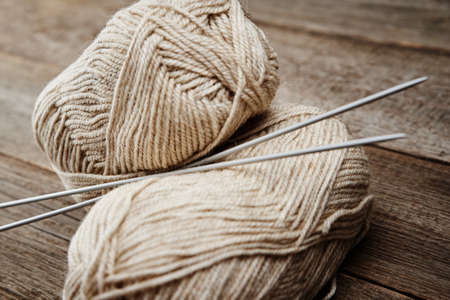 Two skeins of woolen yarn and needles for knitting on wooden backgroundの写真素材