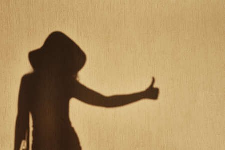 Shadow of woman shows thumb up gesture on the wallの写真素材