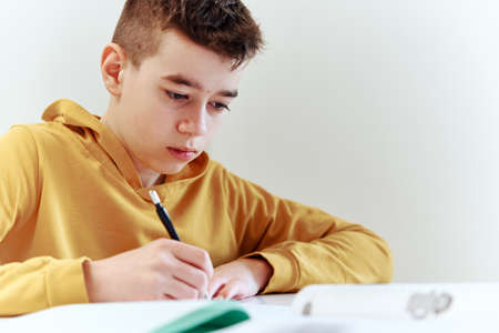 Teenage boy write homework at home. Education concept