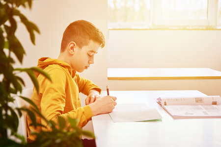 Teenage boy write homework at home. Education concept