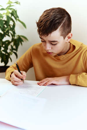 Teenage boy write homework at home. Education conceptの写真素材