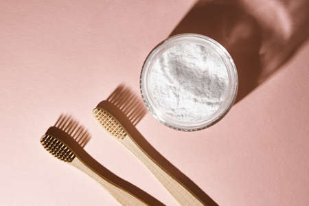 Two bamboo toothbrushes and tooth powder on pink background. Eco friendly and organic product conceptの写真素材