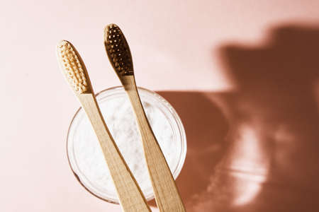 Two bamboo toothbrushes and tooth powder on pink background. Eco friendly and organic product conceptの写真素材
