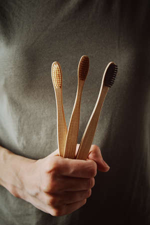 Woman in green t-short holds bamboo toothbrushes. Eco friendly items and zero waste conceptの写真素材
