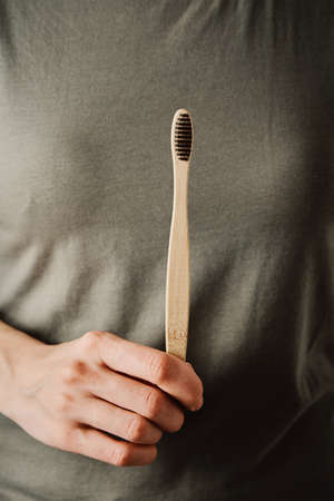 Woman in green t-short holds bamboo toothbrush. Eco friendly items and zero waste conceptの写真素材