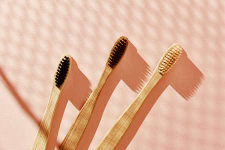 Eco friendly bamboo toothbrushes on pink background. Flat lay top view.の写真素材
