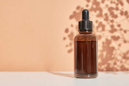 Beaty product package. Cosmetic bottle on pastel beige background with plant leaves shadowsの写真素材