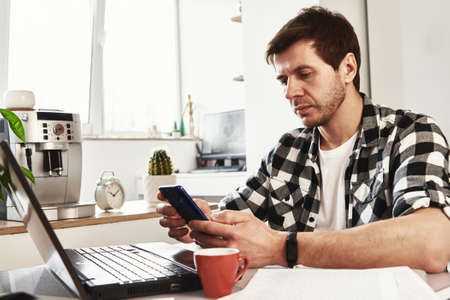 Man working at home office with laptop and smartphone. Online business concept. Remote work