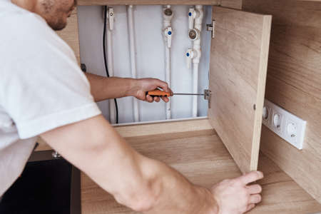 Man mounts door hinge on kitchen furniture doorの写真素材