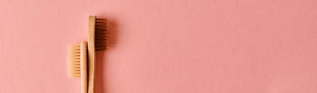 Two eco friendly bamboo toothbrushes on pink background. Flat lay top view.の写真素材