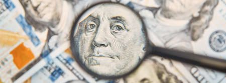 Magnifying glass on dollars bills background. One hundred dollar usd banknotes. Economic and financial problemsの写真素材
