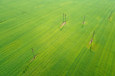 Green agricultural field with electric power transmission towers, aerial view. Transportation electricity.の写真素材