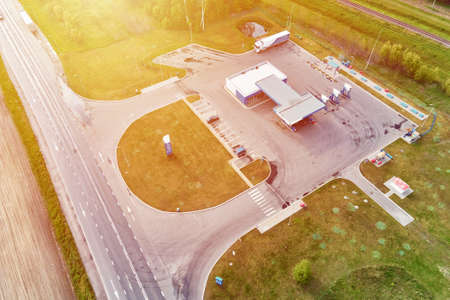 Gas station near highway with moving cars, aerial view.