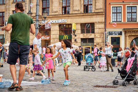 Street performer makes big bubbles on city street to entertain children and tourists in Wroclaw, Poland. Wroclaw, Poland - July 25, 2021のeditorial素材