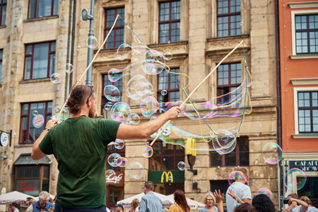 Street performer makes big bubbles on city street to entertain children and tourists in Wroclaw, Poland. Wroclaw, Poland - July 25, 2021のeditorial素材