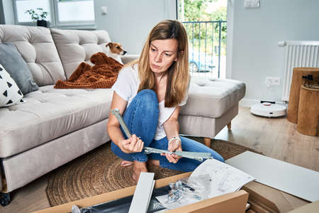Woman reading manual instruction to assemble furniture in the living roomの写真素材