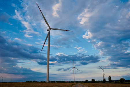 Wind turbine in the field. Landscape with windmills against cloudy sky. Green ecological energy