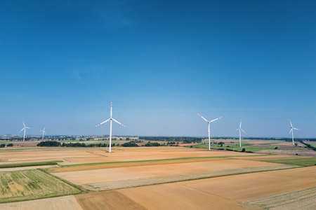 Windmill among agricultural fields. Wind turbine generator at summer day. Wind energy concept....
