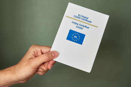 Woman holds covid-19 certificate in hands made in Poland. Vaccination in Europe Union for protection from coronavirusの写真素材