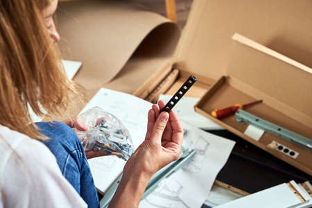 Woman reading manual instruction to assemble furniture in the living room