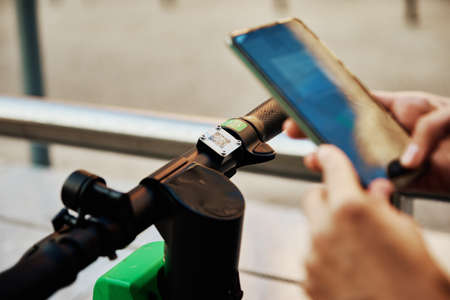 Woman unlock electric scooter for rent using mobile phone app. Modern urban eco transportの写真素材