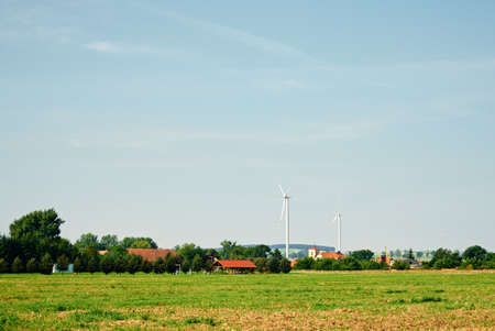 Small european village with residential houses near wind turbine generator in summer day, Green renewable energy conceptの写真素材