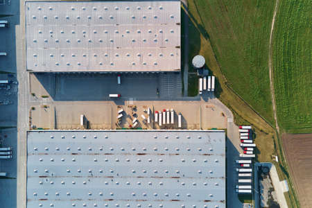 Parking lot for semi trucks near factory, top view. Aerial view of truck trailers parked for waiting loading on factory. Logistics and shippingの写真素材