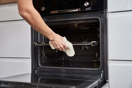 Woman hand open electric oven door with handle. Homemade cooking. Kitchen applianceの写真素材