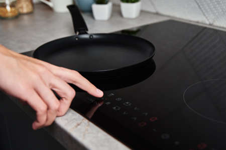 Modern kitchen appliance. Woman hand turn on induction stove to cook. Finger touching sensor button on induction or electrical hobの写真素材