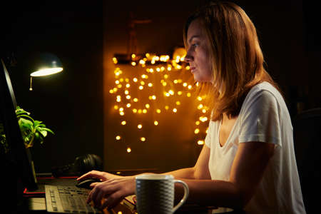 Overtime and remote work. Tired woman works late at computer from home officeの写真素材