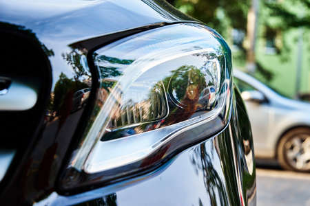 Headlight with halogen lamp on modern black car, close upの写真素材