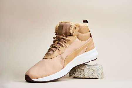 Male boots on beige background. Winter shoes on stone platformの写真素材