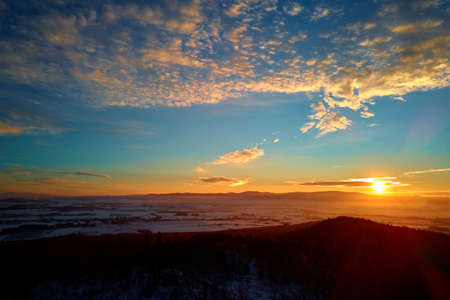 Sunset over mountans with forest covered with snow, beautiful winter landscape, nature background