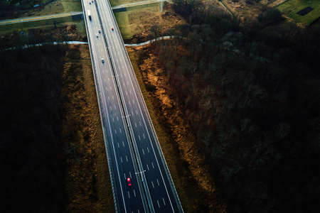 Car traffic moving on highway, aerial view. Countryside road through autumn forest. Road trip,...