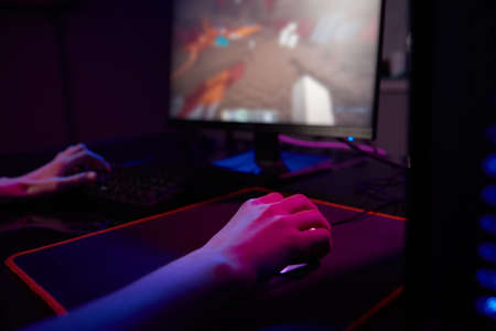 Professional gamer play computer video game in dark room, use neon colored rgb mechanical keyboard,...